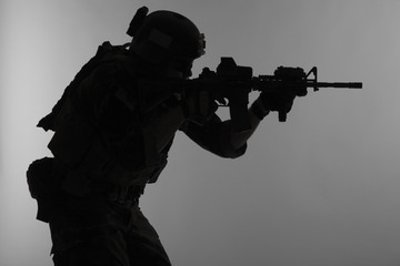 United states Marine Corps special operations command Marsoc raider with weapon aiming a gun. Silhouette of Marine Special Operator gray background