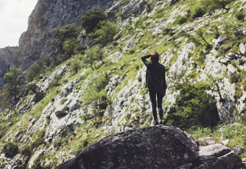 Happy tourist traveler standing on a rock, hiker looking to a valley below in trip in spain, hipster young girl enjoying peak of foggy mountain background green landscape view mockup