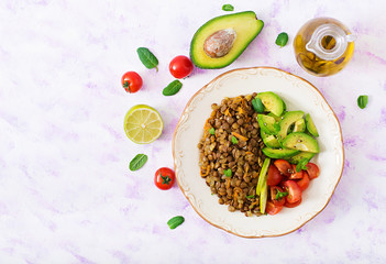 Diet menu. Healthy lifestyle. Lentils porridge and fresh vegetables - tomatoes and avocado on plate. Flat lay. Top view