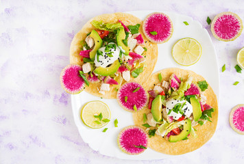 Healthy mexican corn tacos with boiled chicken breast, avocado and watermelon radish and yogurt dressing. Flat lay. Top view