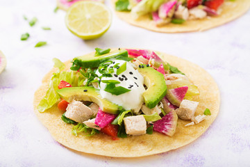 Healthy mexican corn tacos with boiled chicken breast, avocado and watermelon radish and yogurt dressing.