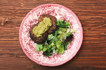 Fried beef patties with pesto sauce and greens