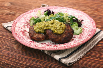 Fried beef patties with pesto sauce and greens