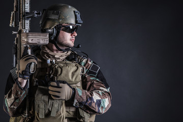 Fototapeta premium United states Marine Corps special operations command Marsoc raider with weapon. Studio shot of Marine Special Operator half-turning black background