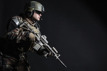 Naklejka premium United states Marine Corps special operations command Marsoc raider with weapon. Studio shot of Marine Special Operator half-turning black background