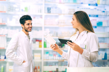 Pharmacists using digital tablet while checking medicine in pharmacy