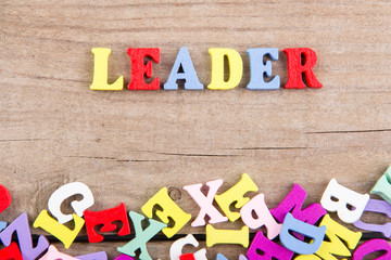 Text "Leader" of colored wooden letters on a wooden background