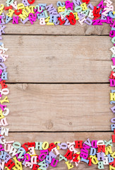 Frame of colored wooden letters on a wooden background
