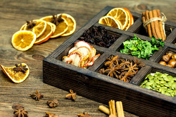wooden box with nuts, spices and dried fruits, mint on wooden background