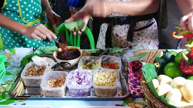 People are doing the Miang Kum (Leaf-Wrapped Bite-Size Appetizer) popular foods Thailand.