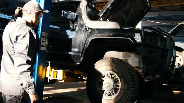 Mechanic lifts SUV in garage automobile service - wheel