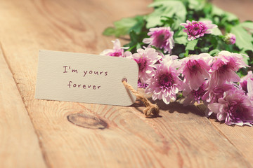 Valentine's Day. Paper tag and pink flowers on wooden table.