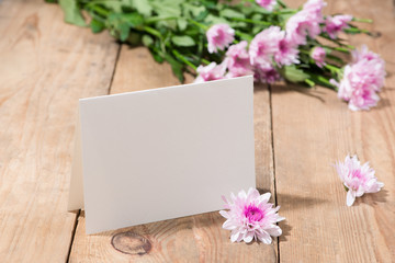 Pink flowers and empty paper for your text on wooden background