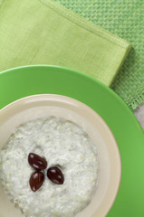 Tzatziki sauce in a bowl and green plate, vertical.