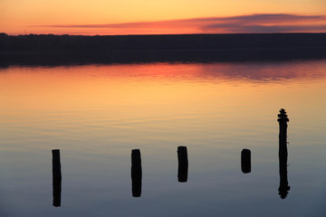 wooden poles reflected on the surface of the salt lake. Kuyalnik