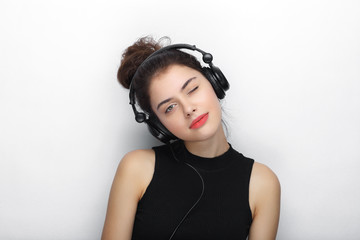 Beauty portrait of young adorable fresh looking brunette woman with long brown healthy curly hair posing in big black professional dj headphones.