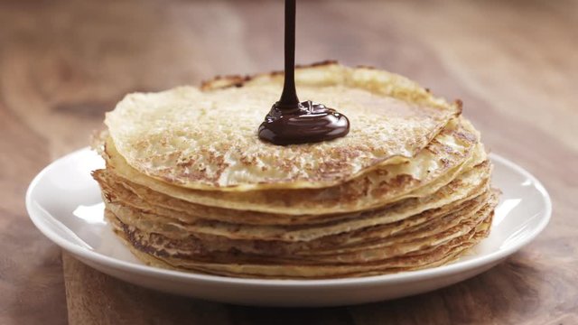 Slow motion of premium dark chocolate pour on freshly made blinis or crepes, 180fps prores footage