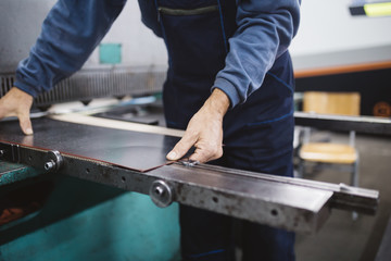 Metallurgy industry. Factory for production of heavy pellet stoves and boilers. Manual worker preparing parts for production. 