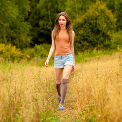 Naklejka na ściany i meble Young beautiful woman walking in a field, summer outdoors