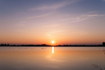 Fototapeta premium Sunset over a flooded rice paddy field