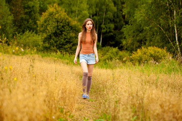 Naklejka na ściany i meble Young beautiful woman walking in a field, summer outdoors