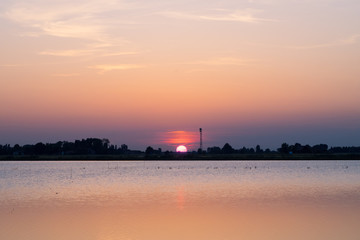 Fototapeta premium Sunset over a flooded rice paddy field in Italy
