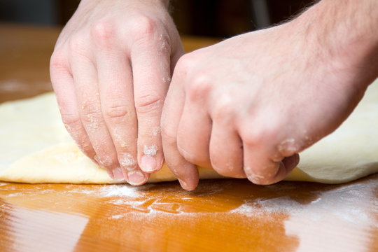Male baker spreading dough for making pizza