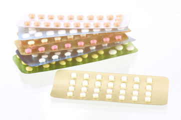 Mini-pills with oral contraceptive pills background in warm ligh