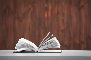 Opened book on table and wooden background