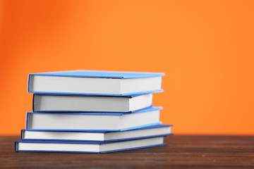 Pile of books on wooden table and orange background