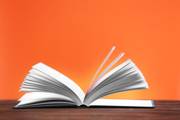 Opened book on wooden table and orange background
