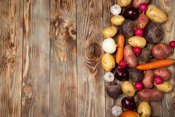 Vegetables. Potatoes, carrots, onions, beets and radishes on a rustic background