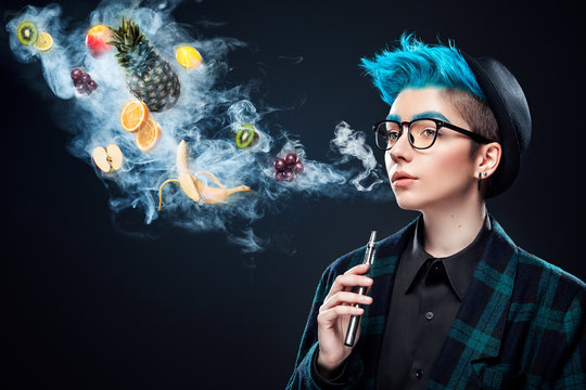 hipster woman with blue hair smoking fruit electronic cigarette on black background. Vape advertisement concept. Copy space
