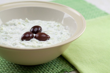 close up of tzatziki sauce decorated with olives