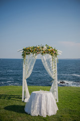 wedding ceremony flowers, arch, chairs with black sea in the background. Beach wedding