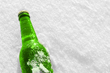 Bottle of cold beer on the snow at sunset. Close up view.