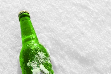 Rollo Bottle of cold beer on the snow at sunset. Close up view. © igorbukhlin