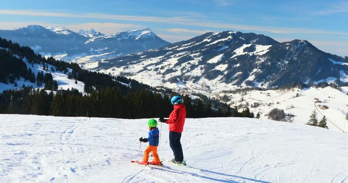 Father and his sun enjoying sunny weather on the ski slopes looking at the Rigi mountain in Swiss Alps, Switzerland