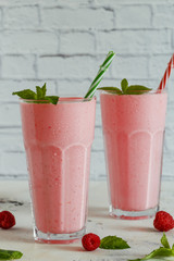 Raspberry milkshake with mint and  straws.