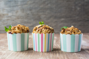 Three muffins in stripy paper cases on the wooden table, selective focus