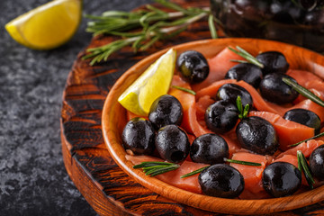 Salmon with olives and lime on a wooden board.