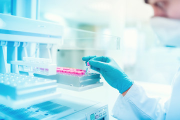 Close up of chemist scientist holding sample and examining test tube in special laboratory