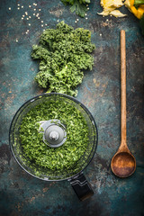 Minced chopped kale leaves on rustic background with wooden cooking spoon and chopper, top view