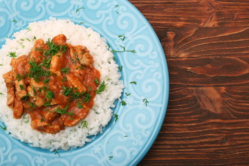 Rice with meat in tomato sause on wooden background