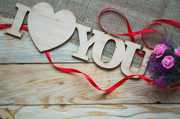 Hearts, flowers, ribbons on a wooden light background
