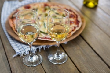 Wine glasses served with pizza in the background