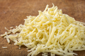 Close up of one heap of grated mix Italian cheese on wood