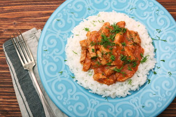 Rice with meat in tomato sause on wooden background