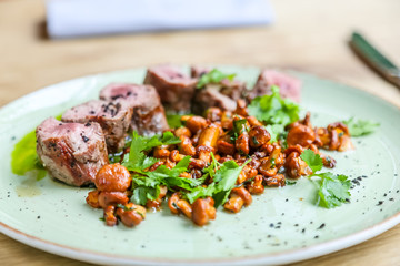 Beef tenderloin with fried chanterelles lying on a plate.