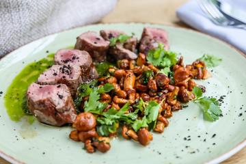 Beef tenderloin with fried chanterelles lying on a plate.